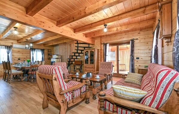 A wooden cabin interior with a dining area, a sofa, and a cabinet.