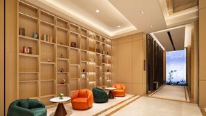 A modern lobby with a long reception desk, multiple seating areas, and a large bookshelf filled with books and decorative items. - Days Hotel BY Wyndham Shenzhen Sanlian (Shenzhen)