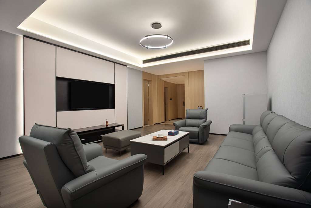 Een moderne woonkamer met een flatscreen televisie, grijze banken en een salontafel.