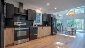 Een moderne keuken met donkere kastjes, roestvrijstalen apparatuur en een eethoek met natuurlijk licht.