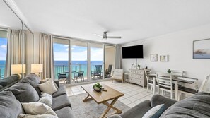 Ein geräumiges Wohnzimmer mit Balkon, einem Flachbildfernseher und einem Esstisch.