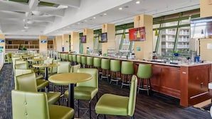 A modern hotel lobby with a long counter, multiple seating areas, and a large window.