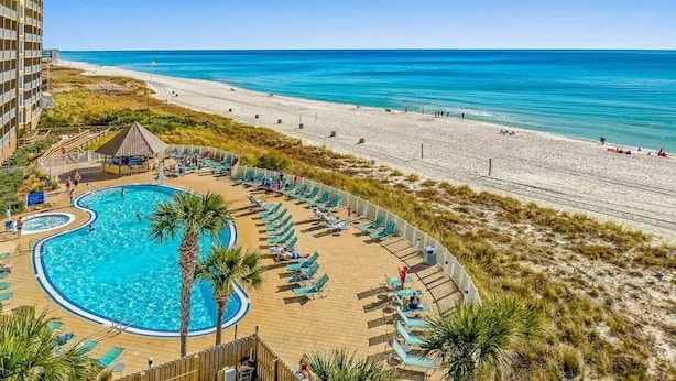 A resort with a swimming pool, beach, and ocean view.