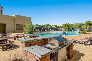 Un espace extérieur avec une piscine, des chaises longues, un barbecue et un bâtiment en arrière-plan.