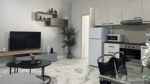 Una cocina moderna con refrigerador, microondas y estufa. Hay un comedor con una mesa y sillas.