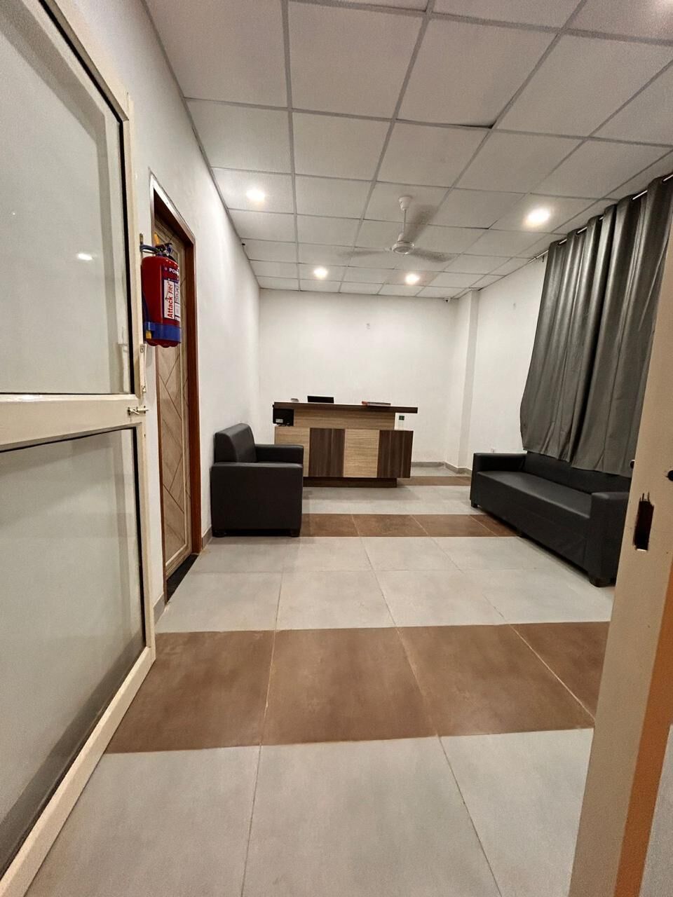 Un lobby moderno de hotel con una recepción, zona de estar y extintor.