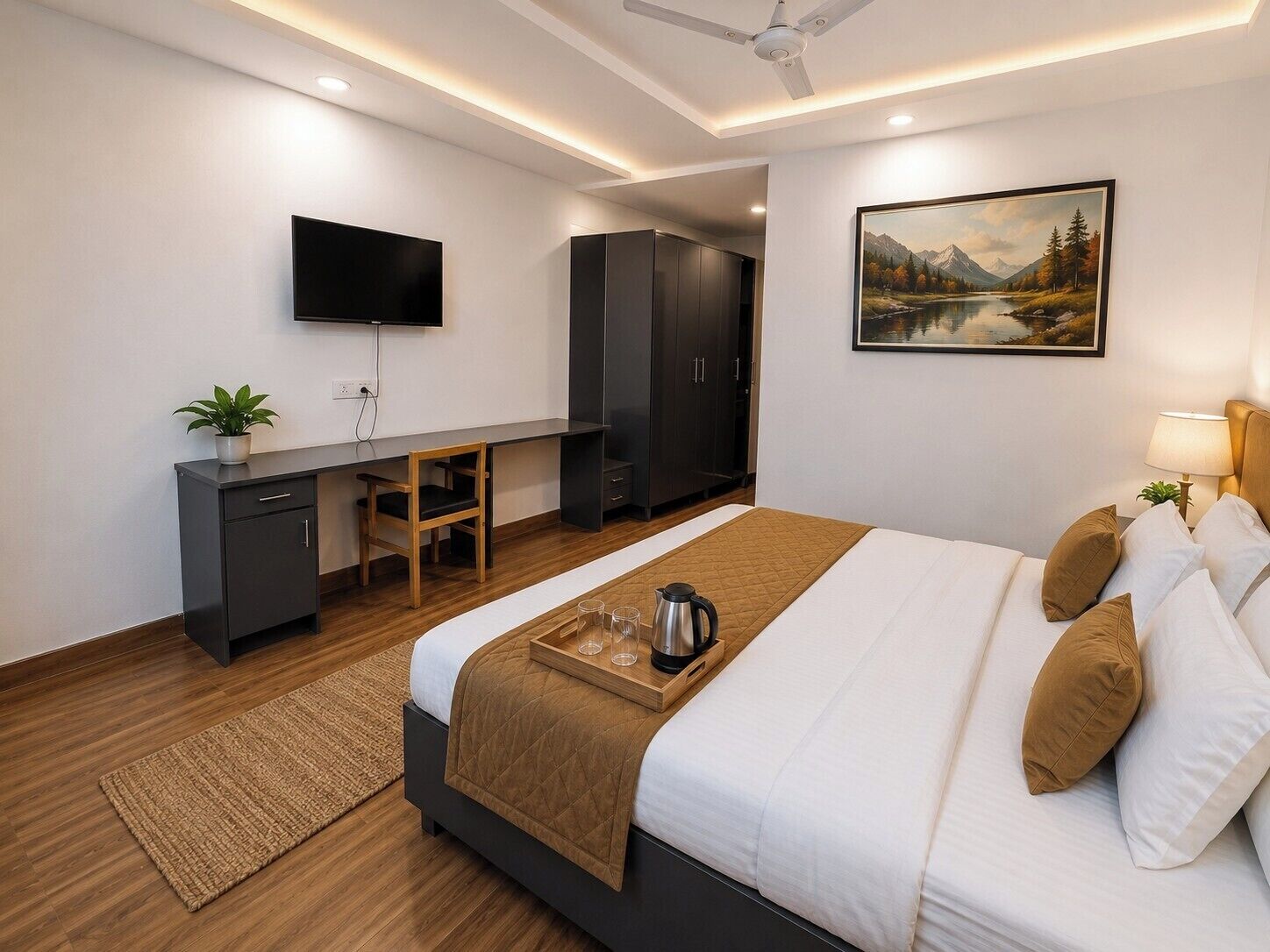 A modern hotel room with a bed, desk, wardrobe, TV, and a painting on the wall.