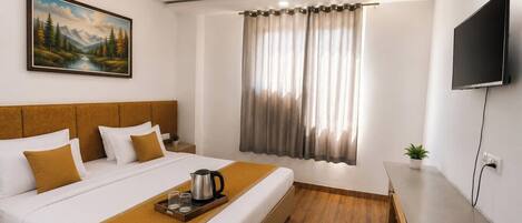 Habitación de hotel con cama, un cuadro, ventilador de techo, televisor y ventana con cortinas.