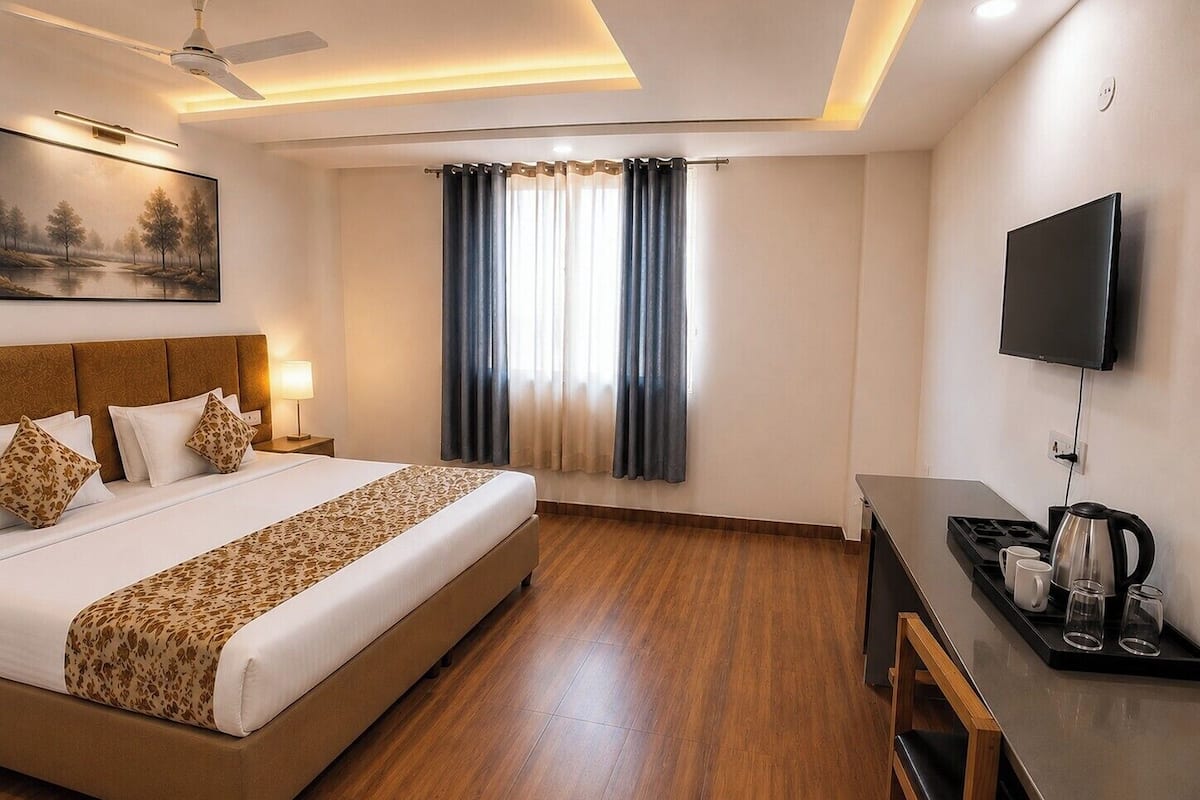 A hotel room with a bed, desk, television, and a painting on the wall.