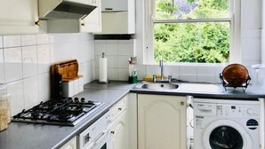 A kitchen with a gas stove, sink, and a washing machine. - 1 Bedroom Flat Sleeps 4 -free Onsite Parking -wifi (London)