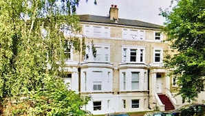 A multi-story building with a symmetrical facade, large windows, and a central staircase leading to the entrance. - 1 Bedroom Flat Sleeps 4 -free Onsite Parking -wifi (London)