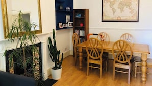 A dining area with a wooden table and chairs, a bookshelf, a world map, and potted plants. - 1 Bedroom Flat Sleeps 4 -free Onsite Parking -wifi (London)