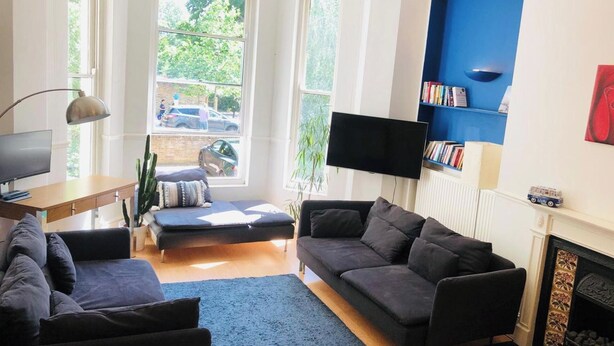 A modern living room with a sofa, a flat-screen TV, a bookshelf, and a fireplace. - 1 Bedroom Flat Sleeps 4 -free Onsite Parking -wifi (London)