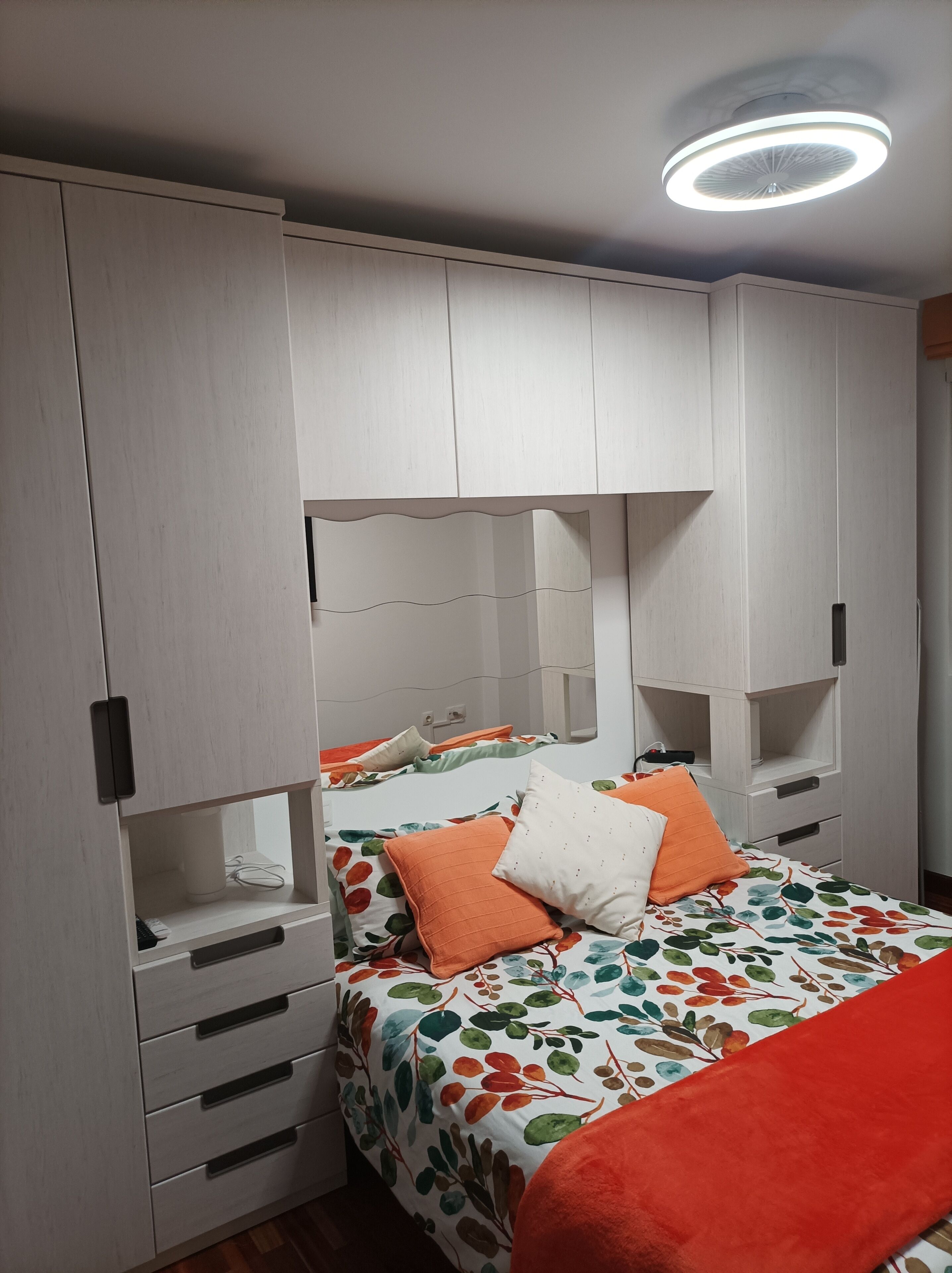 Een slaapkamer met een bed, een kledingkast en een plafondlamp.