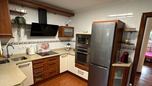 Eine Küche mit Mikrowelle, Backofen und Kühlschrank. Es gibt ein Spülbecken und eine Arbeitsfläche mit einer Pflanze.