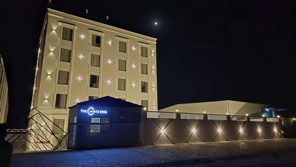 Um hotel com uma placa de destaque que diz "THE WHITE RING" e uma entrada com portão.