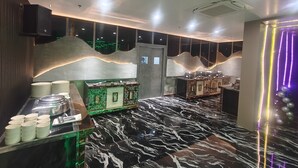 Un interior moderno con piso de mármol, una zona de buffet con platos y fuentes, y una pared decorativa con diseño ondulado.