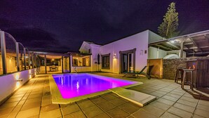 Une piscine dotée d’une terrasse carrelée et d’un espace salon abrité.