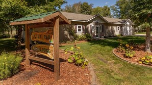 A lodge with a wooden sign reading "Lily Pad Lodge" surrounded by a well-maintained garden and trees. - Lily Pad Lodge on Pelican Lake (Pequot Lakes)