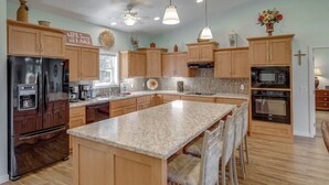 A spacious kitchen with wooden cabinets, granite countertops, and modern appliances including a refrigerator, oven, and microwave. - Lily Pad Lodge on Pelican Lake (Pequot Lakes)