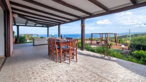 An outdoor patio with a wooden table and chairs, a pergola, and a view of the ocean. - Villa 'Patrizia' with Sea View, Wi-Fi and Air Conditioning (Castelsardo)