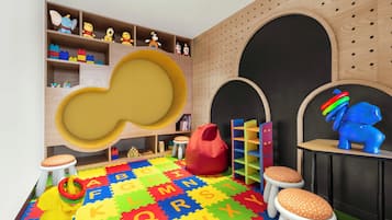 Children can play and learn in this vibrant playroom with a large play structure, soft seating, and alphabet-themed mats.