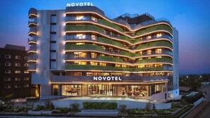A modern hotel with multiple balconies, a prominent 'NOVOTEL' sign, and a well-lit entrance. - Novotel GOA Panjim (Panaji)