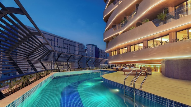 A modern hotel with a rooftop pool, outdoor seating, and balconies with plants. - Novotel GOA Panjim (Panaji)