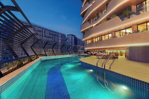 A modern hotel with a rooftop pool, outdoor seating, and balconies with plants. - Novotel GOA Panjim (Panaji)
