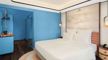 Habitación de hotel moderna con una cama grande, una mesita de noche y un baño visible a través de una puerta abierta.