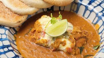 Una ciotola di curry con pane e spicchio di lime.