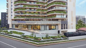 A multi-story hotel with balconies, a ground-level restaurant, and a pool area. - Novotel GOA Panjim (Panaji)