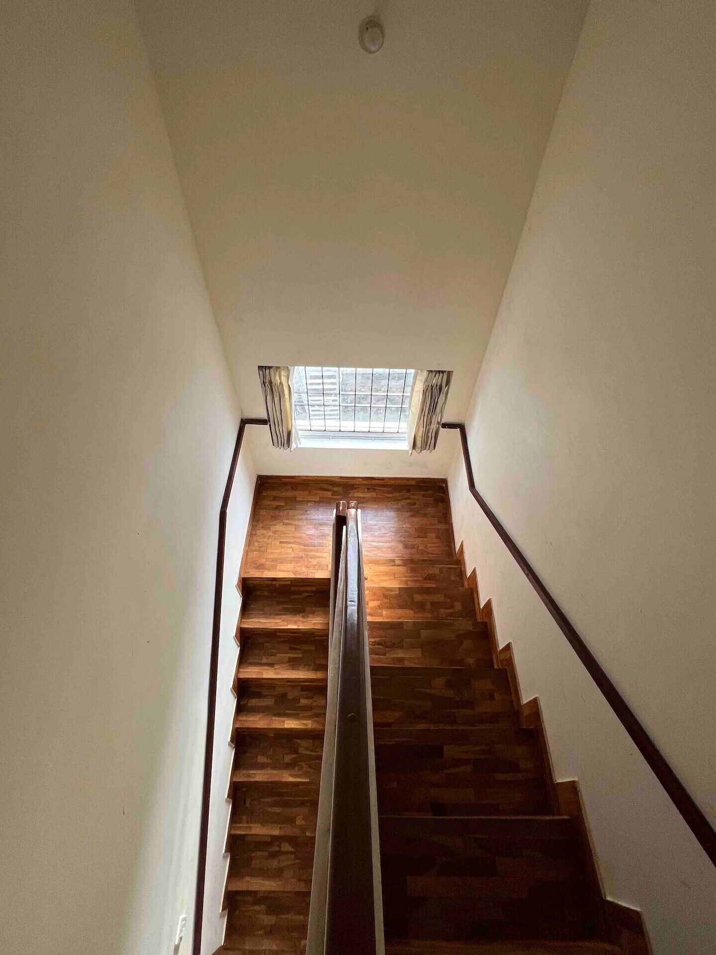 A wooden staircase with a skylight at the top.