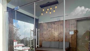 A modern room with a glass wall, wooden panel wall, and a bench. - Sky Top Villa (Kodaikanal)