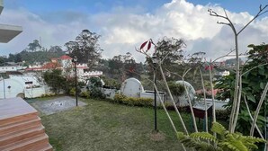 A residential area with a grassy lawn, a staircase, and a view of houses in the background. - Sky Top Villa (Kodaikanal)