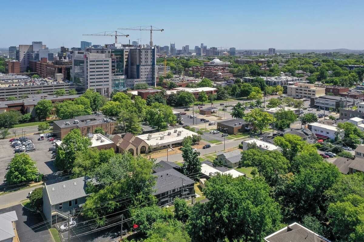 Luchtbeeld van een stadsgezicht met verschillende gebouwen, waaronder een opvallend bouwterrein met kranen.