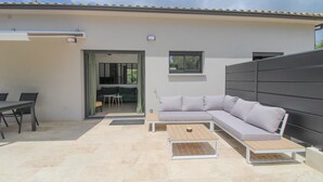 Een terras buiten met een bank, tafel en stoelen.