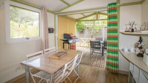 Un porxo cobert amb taula de dinar, cadires, una barbacoa i vista a l'exterior.