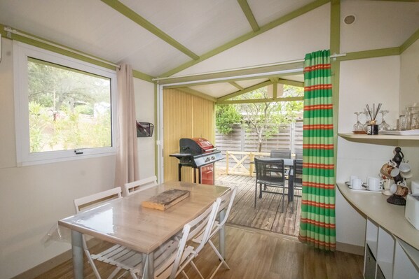 A covered patio with a dining table, chairs, a grill, and a view of the outdoors.