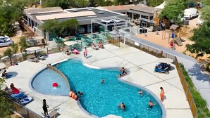 Una piscina de forma singular, envoltada de gandules i ombrel·les.