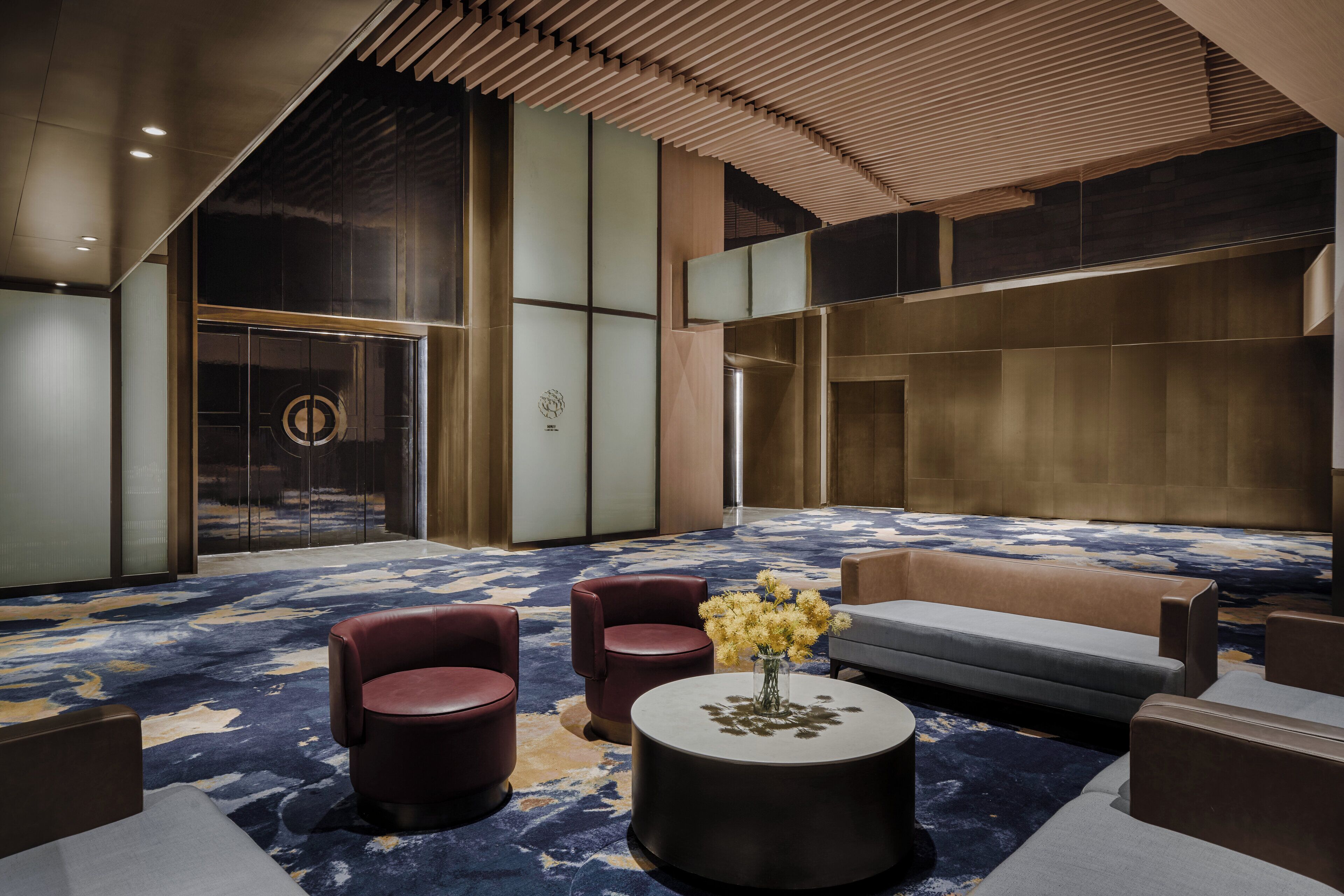 A modern lobby with a large seating area, a central coffee table, and a decorative vase.