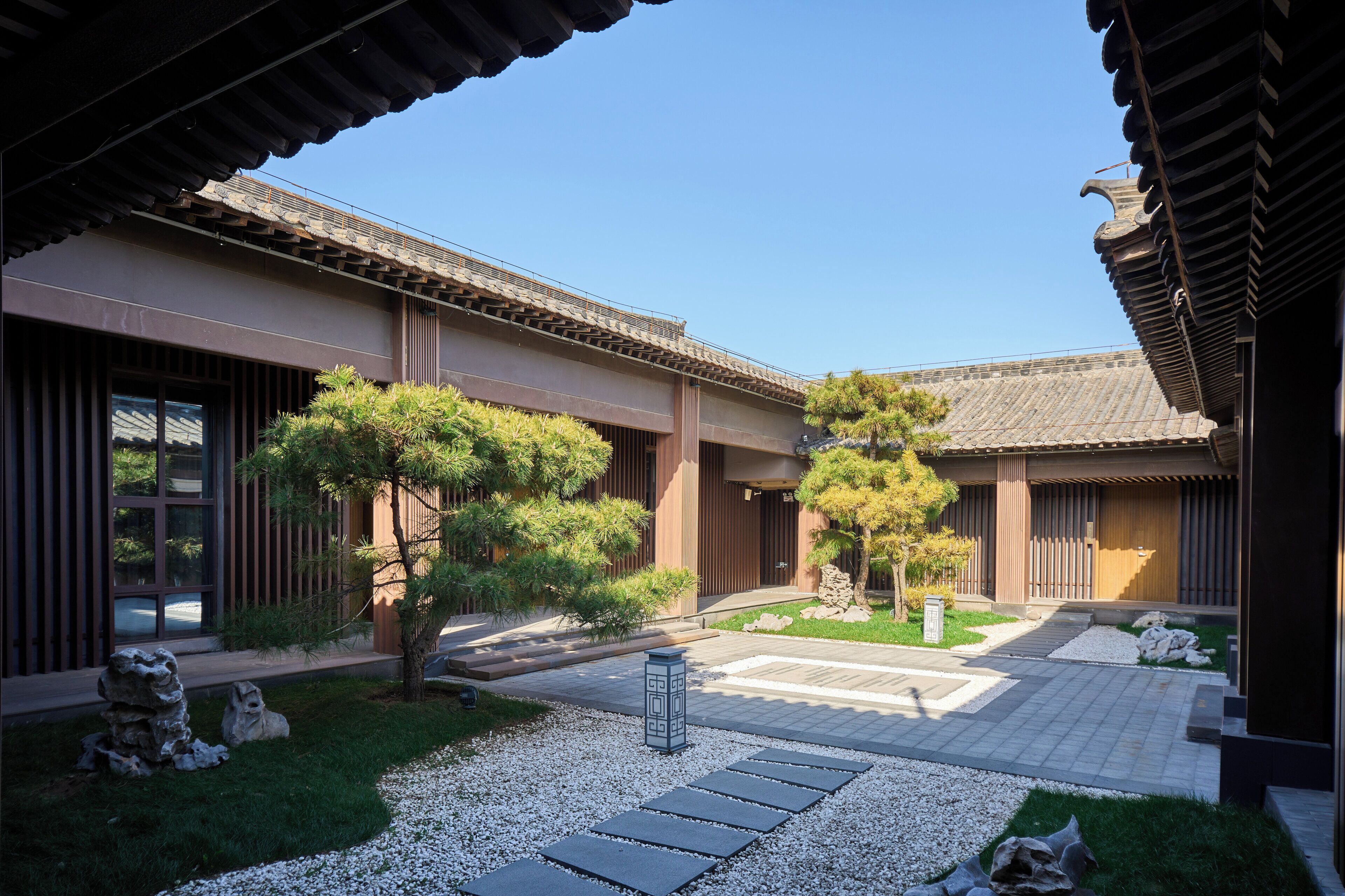 Edificio japonés tradicional con patio, farol de piedra y follaje bien cuidado.