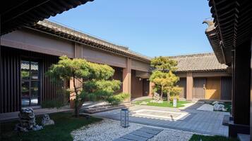 Edificio japonés tradicional con patio, farol de piedra y follaje bien cuidado.