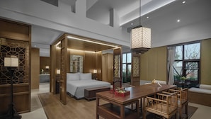 Una habitación de hotel moderna con cama, mesita de noche y una zona de comedor con sillas.