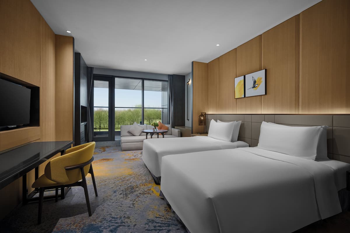 Una habitación de hotel con dos camas, un sofá, un escritorio y un televisor.