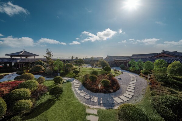 A traditional Korean garden with a central circular pathway, surrounded by neatly trimmed bushes and trees, and traditional Korean architecture in the background. - voco Zhengzhou Garden Expo by IHG (Zhengzhou)
