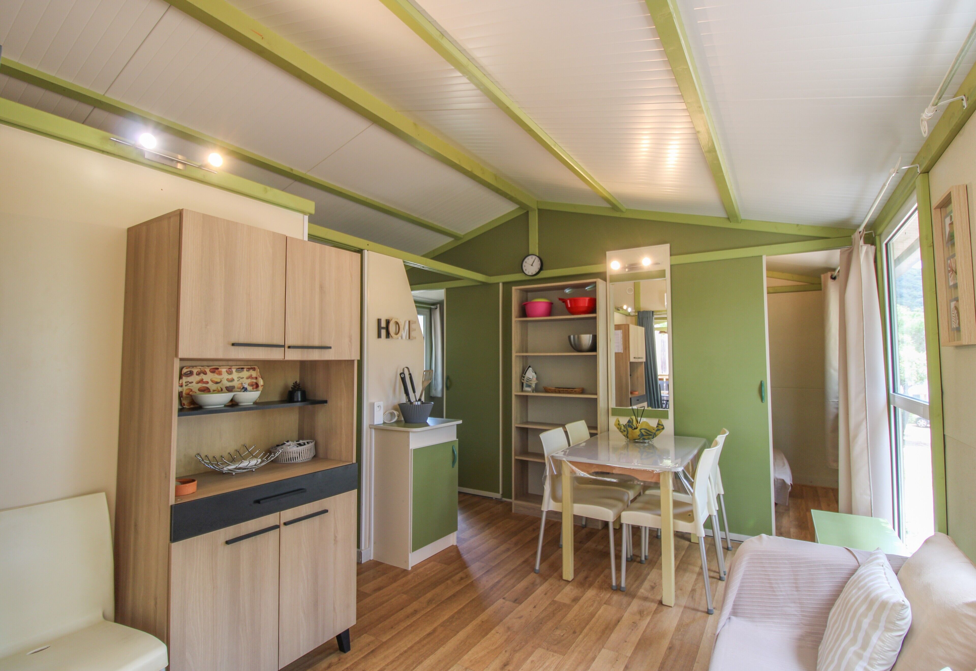 Une cuisine compacte avec des meubles en bois, un coin repas avec une table et des chaises, et un petit coin salon avec un canapé.