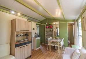 Uma cozinha compacta com armários de madeira, uma área de refeições com mesa e cadeiras, e um pequeno espaço de estar com um sofá.