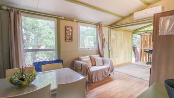 Une pièce avec un plancher en bois, un lit, une table avec des chaises et une fenêtre avec des rideaux.