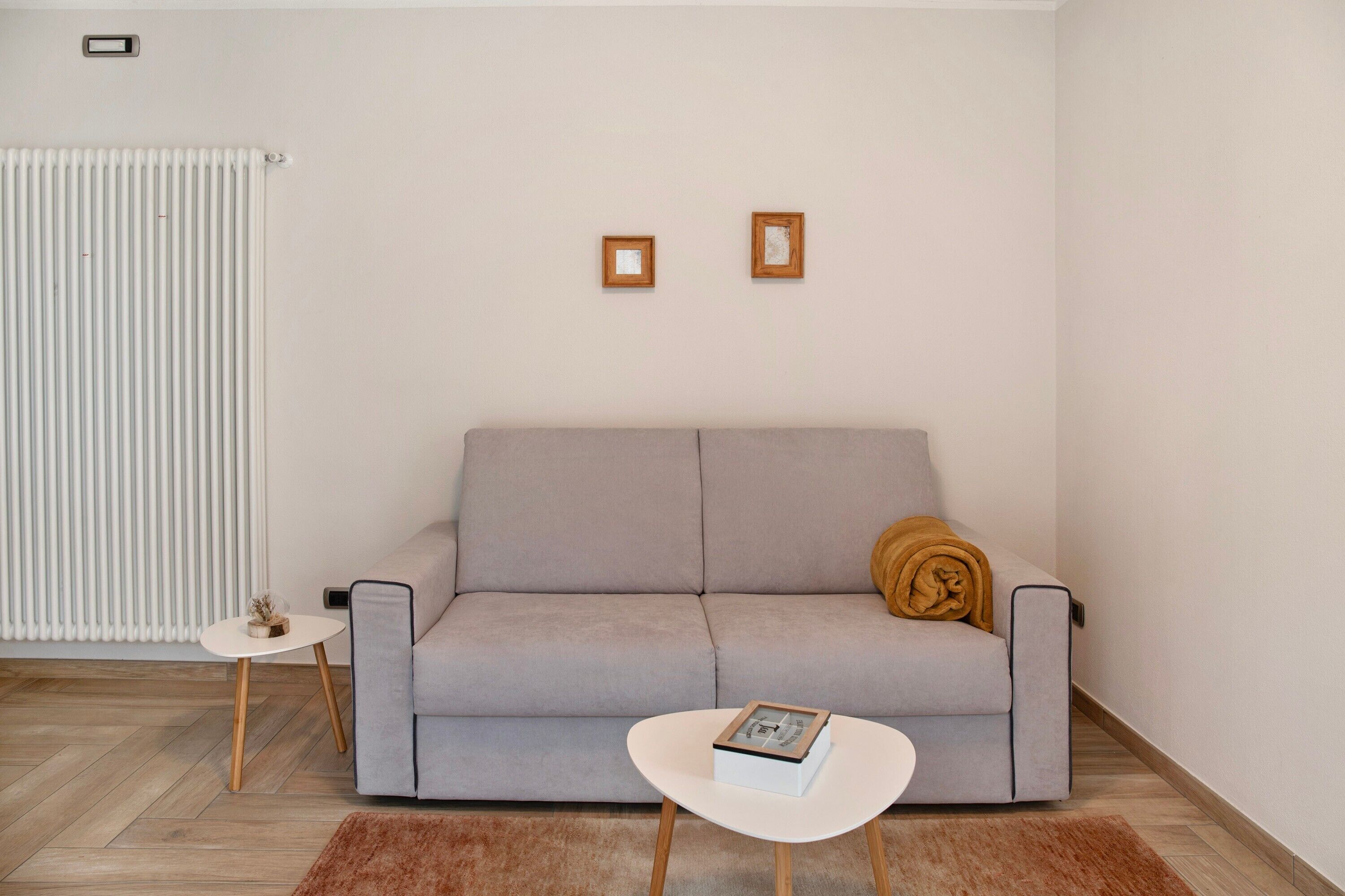 A modern living room with a grey sofa, a small white table, and a brown rug.